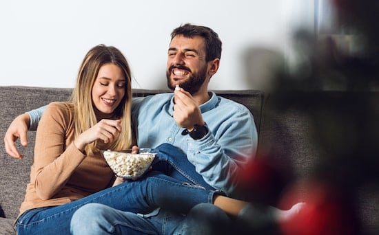 man and woman eating popcorn and laughing